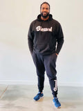 A man wearing a Black Unisex Hoodie and black jogger pants with the word "blessed" written in white font.