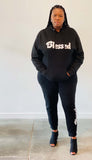 A woman wearing a Black Unisex Hoodie and black jogger pants with the word "blessed" written in white font.
